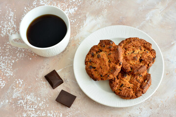 oatmeal cookies with chocolate isolated on white plate with cup of coffee