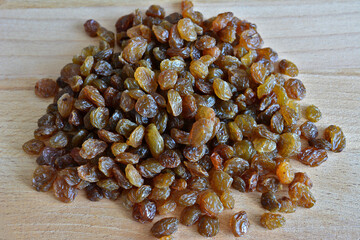 pile of dry raisin on light wooden background isolated, close-up