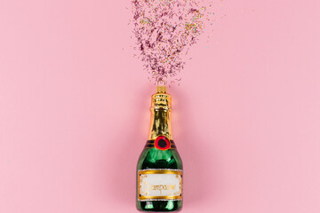 A Christmas tree bauble in the shape of a green champagne bottle. Golden and pink glitter come out...