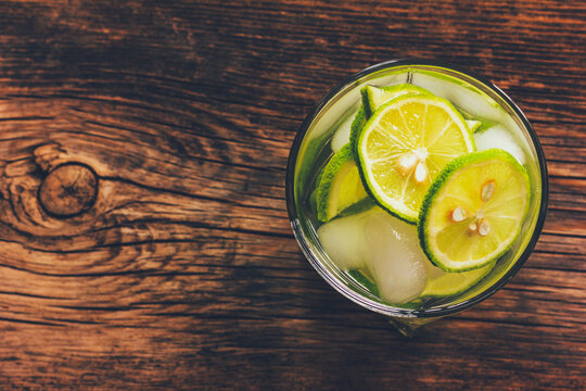 refreshing drink cocktail caipirinha with green lemon with seeds and ice on a wooden background with copy space
