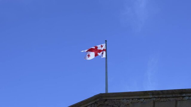 the flag of Georgia flies on the roof of the building