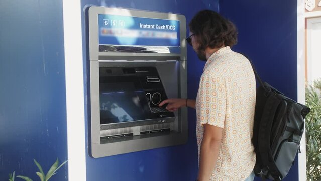 Man using ATM machine withdraw cash outdoor. Inserting card in ATM machine.