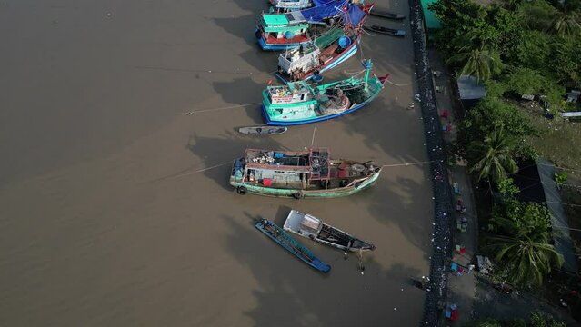 Drone footage along fishermen boats near the pier in Rach Gia city, Kien Giang province. Drone is moving from bottom to the top over the boats.