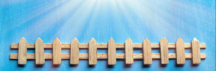 Decorative wooden fence on a blue background. A country fence in the rays of the sun.A white fence made of wood.