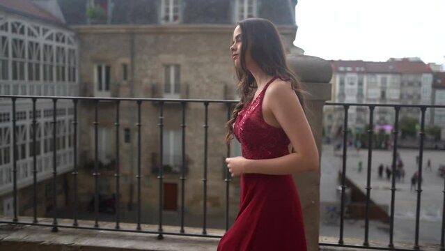 Caucasian model in a red dress walking through the city of Vitoria, Araba. Spain