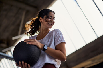 Young woman with a ball laughing in a gym