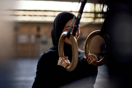 Smiling muslim woman doing suspension training