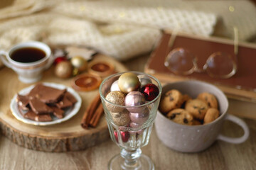 Cup of tea or coffee, various sweets and spices, Christmas decorations, comfy blanket, books and glasses. Selective focus.