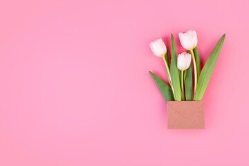 bouquet of white tulips in a craft envelope. surprise concept. isolated on pastel pink background. Object for design to women's day, mother's day, anniversary, valentine day. Minimalism concept