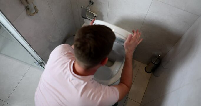 Young man vomits in toilet food poisoning