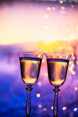 Christmas New Year background concept. Two glasses with champagne sparkling wine on a winter evening background. The atmosphere of celebration, magic and happiness.
