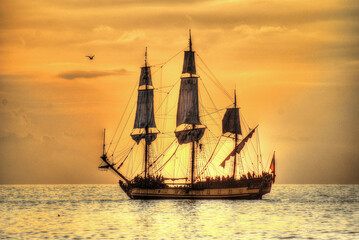 Sunset over the sea. Soft orange sunlight. Romantic sea background with sailing ship.