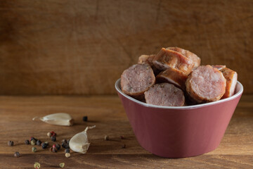 Slices of smoked pork sausages in bowl with spices