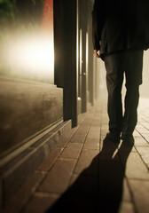 Man in suit walks on sidewalk along buildings in a misty city. Rear view. 3D render.