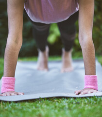 Yoga, hands and mat with a woman plank closeup outdoor in a grass park for workout or training. Wellness, health and fitness with a female yogi exercising outside on grass in a garden for balance