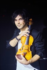 Violinist a player with a violin instrument in his hands. Artist of classical music or alternative music direction. Concept of stage art and performance.