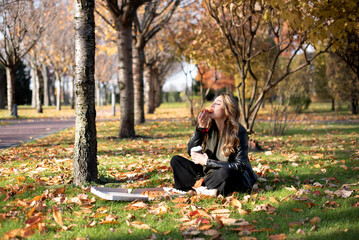 Young girl eats pizza in the park enjoying autumn nature..