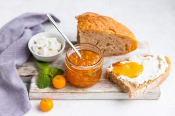 Sliced artisan homemade bread with ricotta or cottage cheese and orange jam on light background....