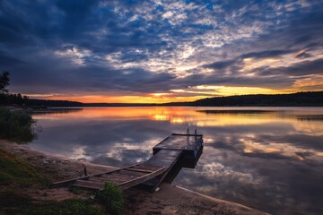 Sunrise on the lake. Wooden small pier in the morning scenery.