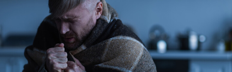 stressed man wrapped in warm blanket sitting in twilight with closed eyes, banner.