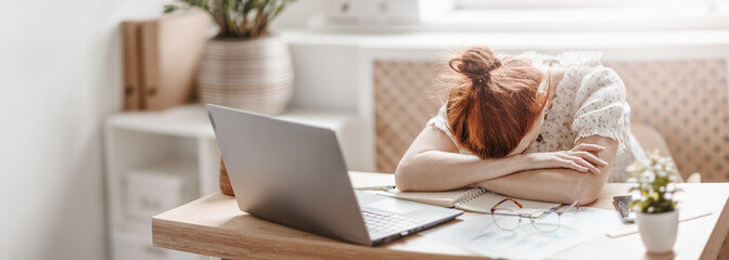 Tired woman putting her head on her hands on the desk in the office