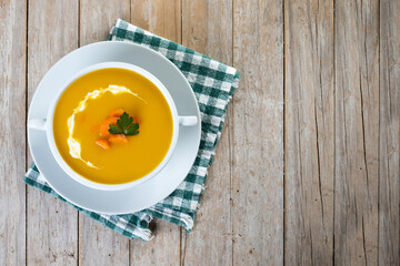 Carrot soup with cream and parsley on wooden table. Top view. Copy space