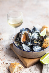 Blue mussels in creamy white wine sauce served with lime and bread. Stew mussels in wine, leek and blue cheese. Seafood.