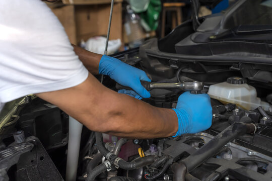 Close up machanic hands using wrench fixing opened hood car in auto repair shop, Car Mechanic Concept