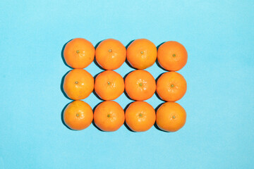 Juicy, natural and irregular tangerines on a blue background, with copy space, forming a rectangle in a pop art style