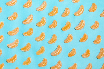 Juicy and healthy tangerine segments, irregularly shaped, on a blue background, forming a pop art style image and texture