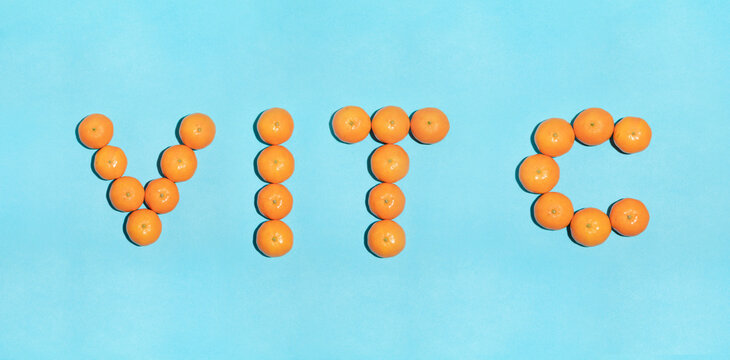 Juicy tangerines on a blue background, arranged in letters, forming the word VIT C, short for vitamin, in a pop art style