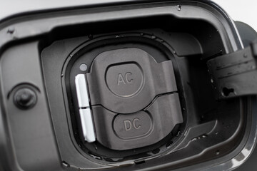Close up of electric vehicle AC and DC charge port options on modern grey vehicle