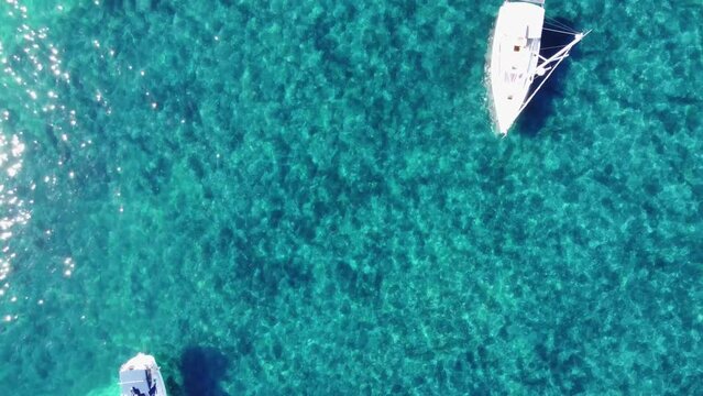Flying over little boats and people swiming in clear watter, up to the port of Saint Honorat island part of the Iles de L&eacute;rins, next to Cannes in south of France in mediterranean sea