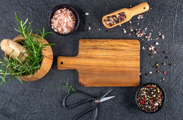 Fresh vegetables on wooden mortar and cutting board for cooking, dark background.