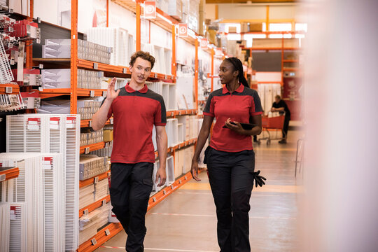 Male and female sales staff talking while walking in hardware store