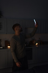 man holding cellphone in raised hand while catching signal during power outage.