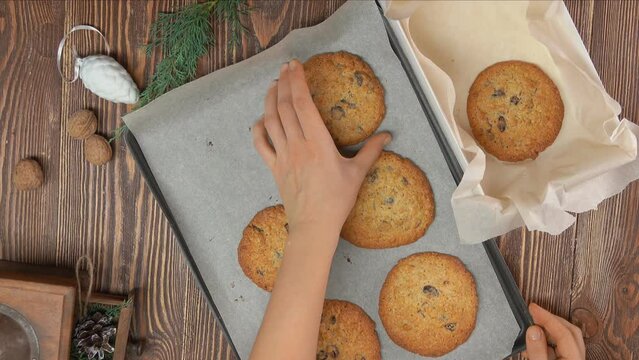 Female hand takes oatmeal coockies from tray and puts it into the Christmas box