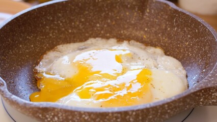 Close-up frying pan with scrambled eggs being stirred with fork to make simple scrambled egg. Eggs breakfast quick and nutritious. Habitual preparation of scrambled eggs for breakfast is daily routine