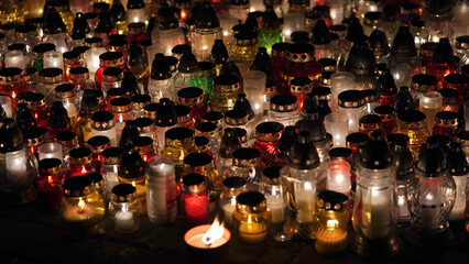 Lot of burning candles at night in cemetery.Glass inextinguishable lamps for cemetery.Day of remembrance and mourning for the dead.All Saints' Day.Commemorative candles as decor.Cemetery lamps.