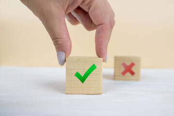 Hand of a businessman chooses checkmark and x sign symbol on  cube block