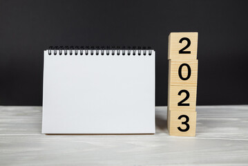 2023 calendar mockup.Text 2023 on wooden cubes. Place for your text in notepad, calendar layout. New Year. startup concept.