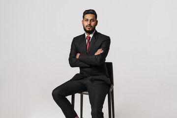 Young indian man wearing suit posing while sitting on chair