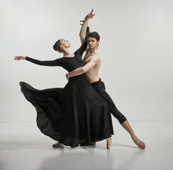 Young man and woman, ballet dancers performing isolated over grey studio background Tenderness and...