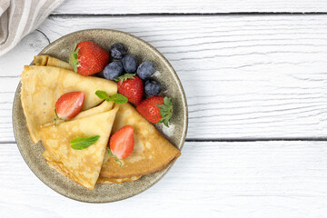 French crepes, pancakes or Russian bliny with berries on a white background Pancakes with berries. Top view, copy space.