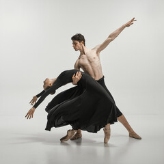 Young man and woman, ballet dancers performing on stage isolated over grey studio background. Lightness and freedom © master1305