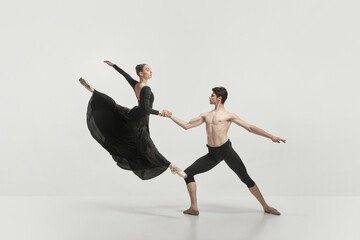 Young man and woman, ballet dancers performing isolated over grey studio background. Flying high © master1305