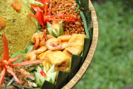Side dishes from Nasi Tumpeng, such as fried shrimp, dried tempeh, fried tofu, vegetables, and cucumber