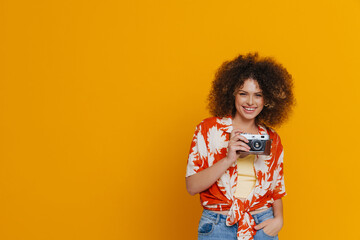 Young beautiful attractive smiling happy curly woman holding vintage camera