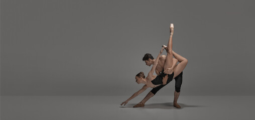 Young man and woman, ballet dancers performing on stage isolated over dark grey studio background. FLyer