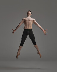 Portrait of young muscular man, ballet dancer performing isolated over dark grey studio background. Metamorphosis © master1305